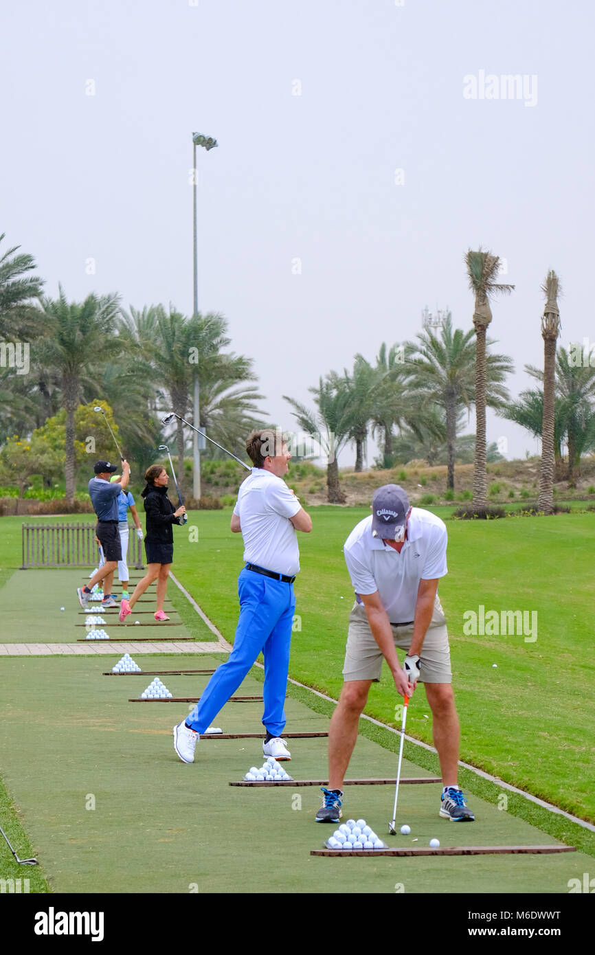 Groupe de joueurs de golf train / pratiquant à Saadiyat Beach Golf Course, Abu Dhabi ÉMIRATS ARABES UNIS. Banque D'Images