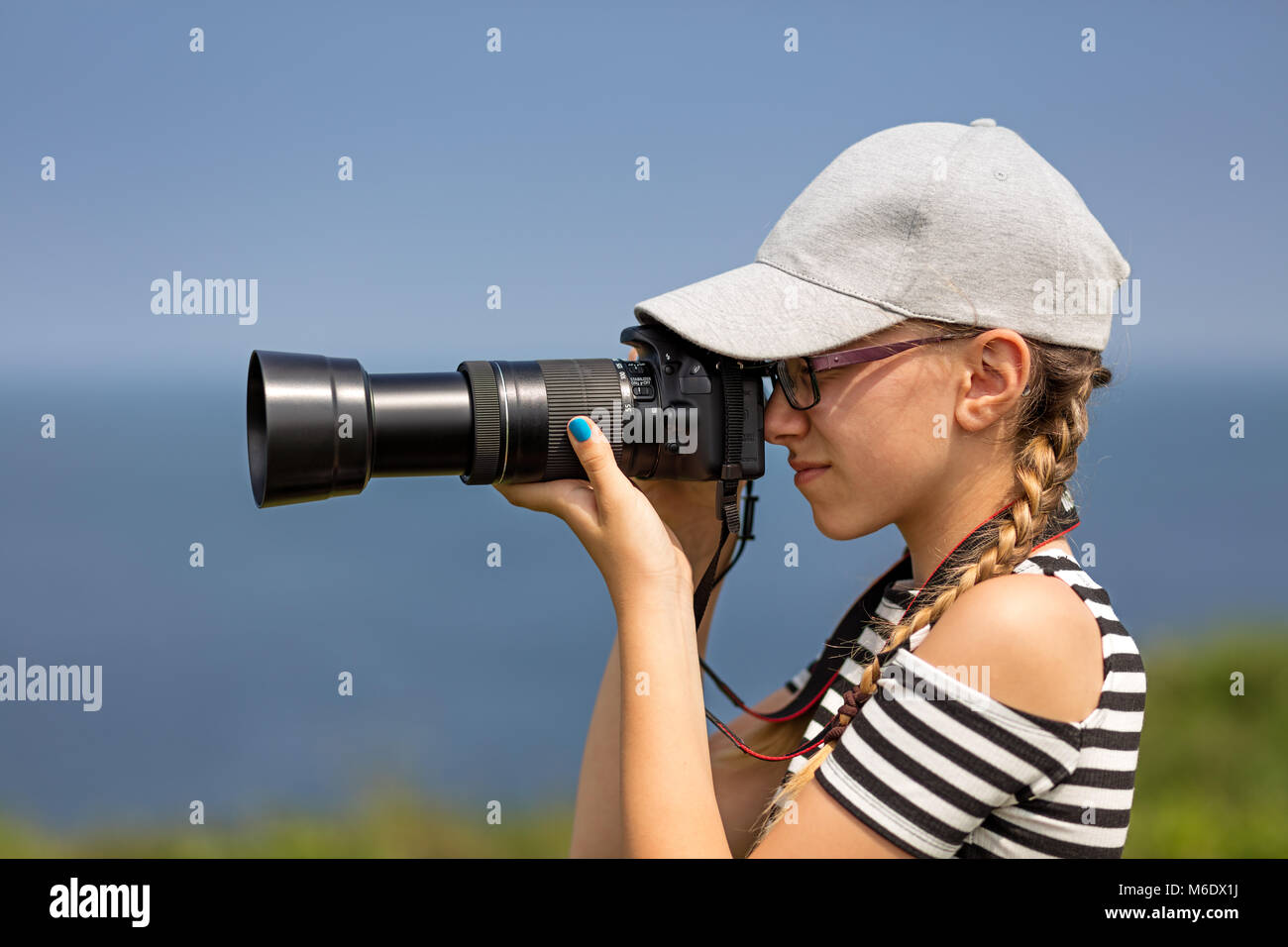 12 ans, fille, et prendre des photos avec un objectif long dans un magnifique paysage de falaises irlandaises Banque D'Images