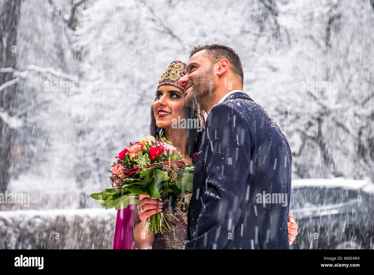 Couple heureux en robe de mariage traditionnelle turque au cours de leur mariage dans une tempête de neige Banque D'Images