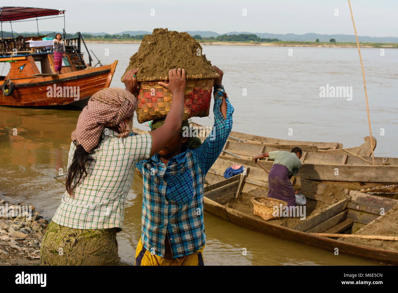 Mandalay : femme homme sable de déchargement avec panier de cargo à l'Ayeyarwady (Irrawaddy) Rivière, travail lourd, , Région de Mandalay, Myanmar (Birmanie) Banque D'Images