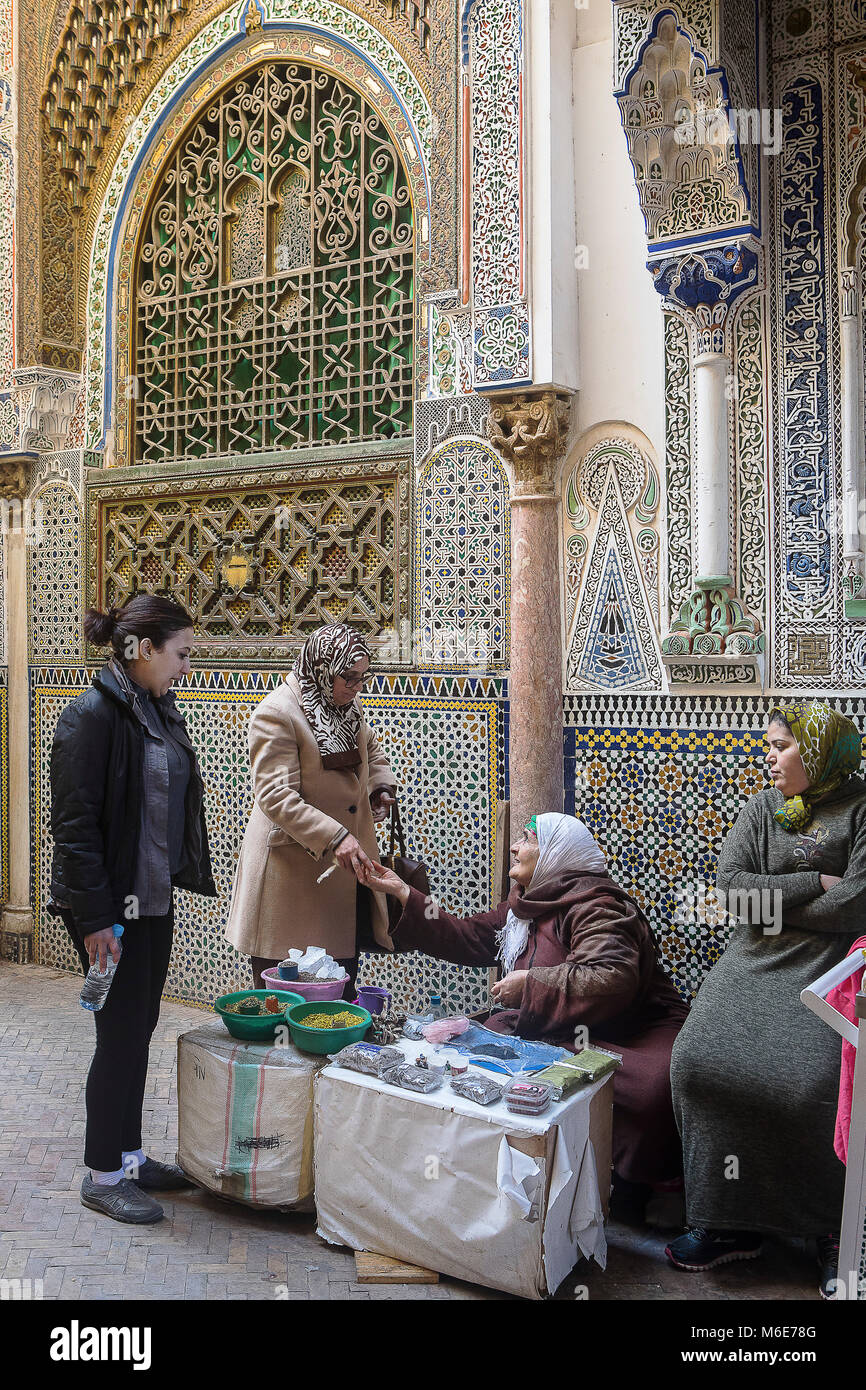 Boutique d'encens et le henné, clients et vendeuse, en arrière-plan façade de Zaouia (Tombeau) de Moulay Idriss II, Médina, à Fès. Maroc Banque D'Images