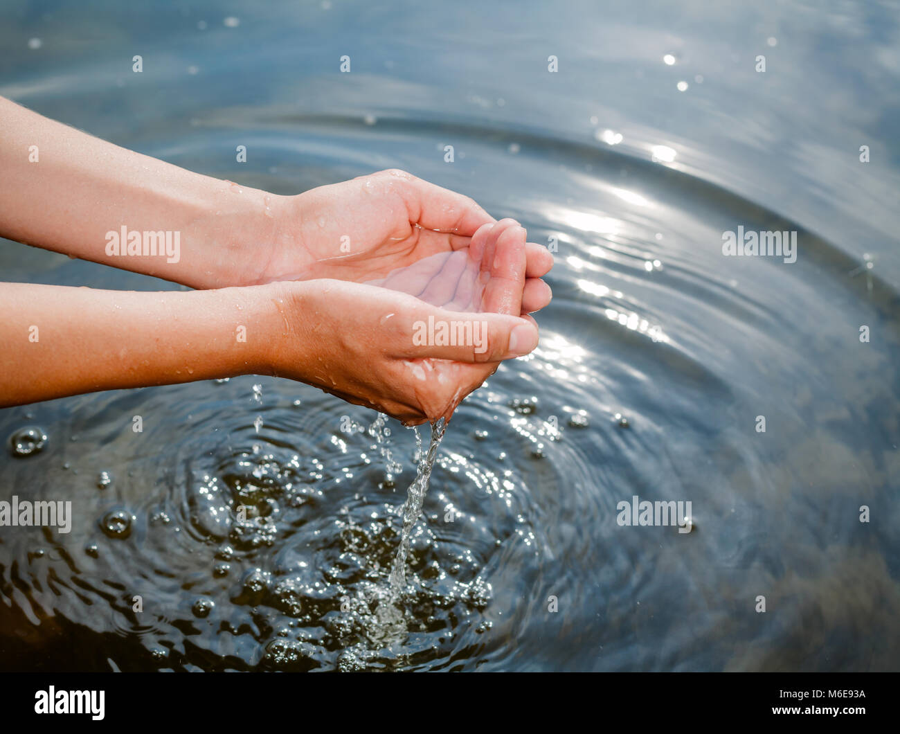 Femme de prendre l'eau non filtrée de matières premières d'une source naturelle en creux des mains Banque D'Images