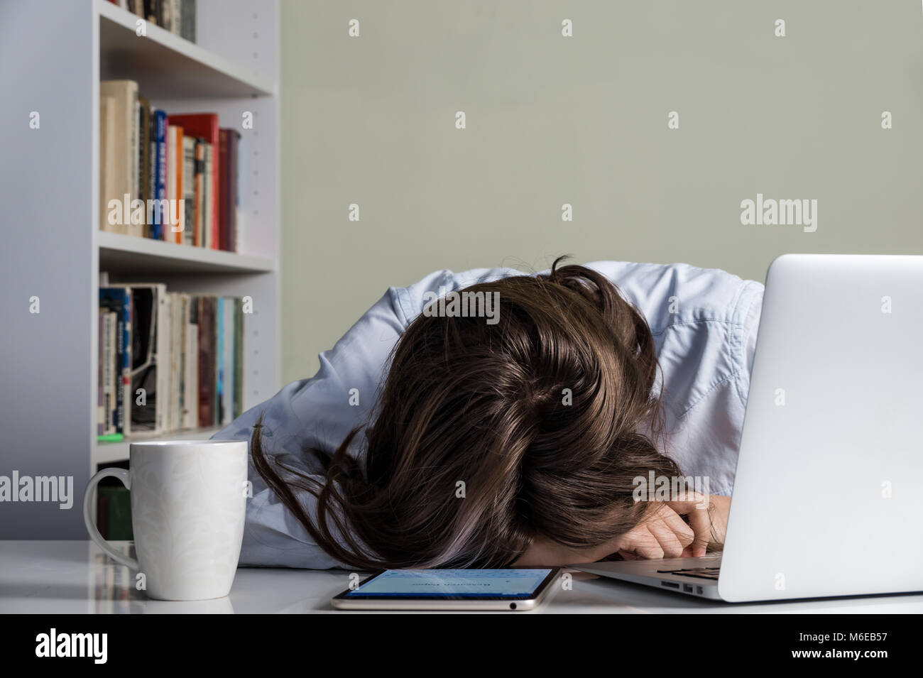 Fatigué girl posant sa tête sur la table de travail avec ordinateur Banque D'Images