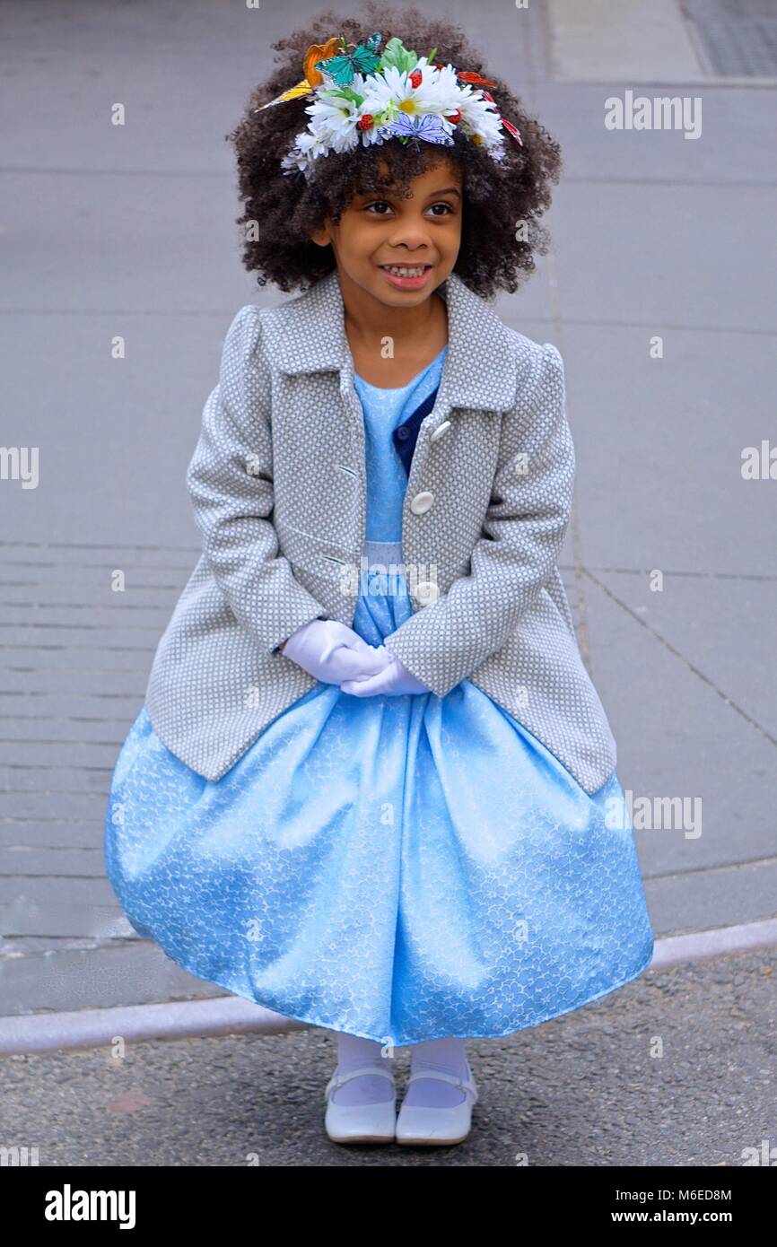 New York, New York, USA : Une petite fille dans une robe bleue et bonnet fleuri pose pour des photos lors de l'assemblée, Cinquième Avenue Easter Parade. Banque D'Images