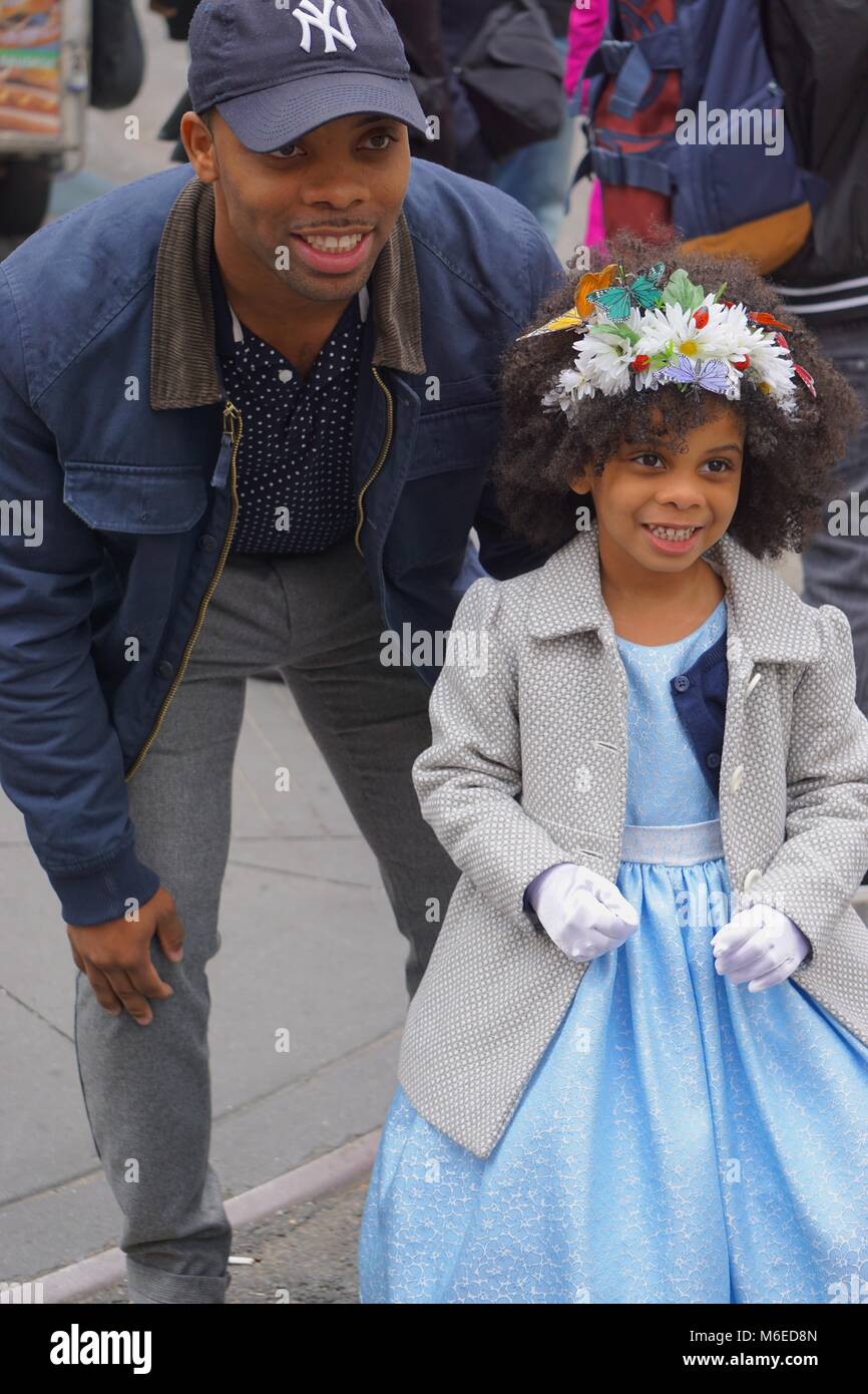 New York, New York, USA : UN NY Yankees ventilateur et d'une petite fille dans une robe bleue et bonnet fleuri à l'assemblée annuelle, Cinquième Avenue Easter Parade. Banque D'Images