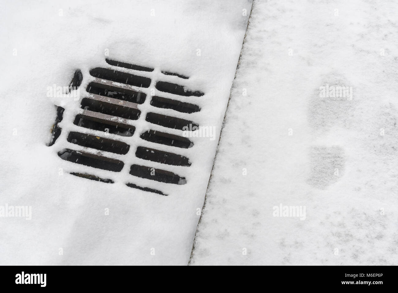 Sur le trottoir couvert de neige / grille de drainage des routes au cours de la bête de l'Est 2018 vortex polaire neige qui a causé des problèmes pour les navetteurs. Banque D'Images