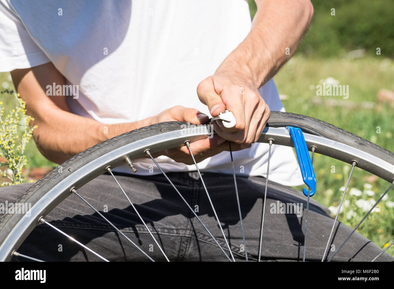 Close up image des personnes mains en utilisant les leviers des pneus pour remplacer le tube intérieur de roue de bicyclette Banque D'Images
