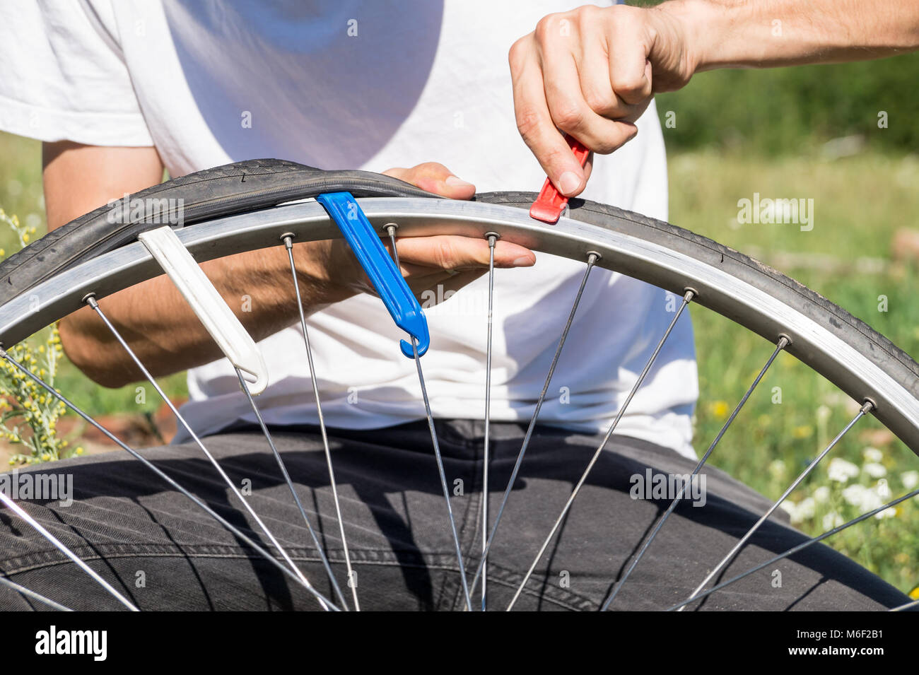 Close up image des personnes mains en utilisant les leviers des pneus pour remplacer le tube intérieur de roue de bicyclette Banque D'Images