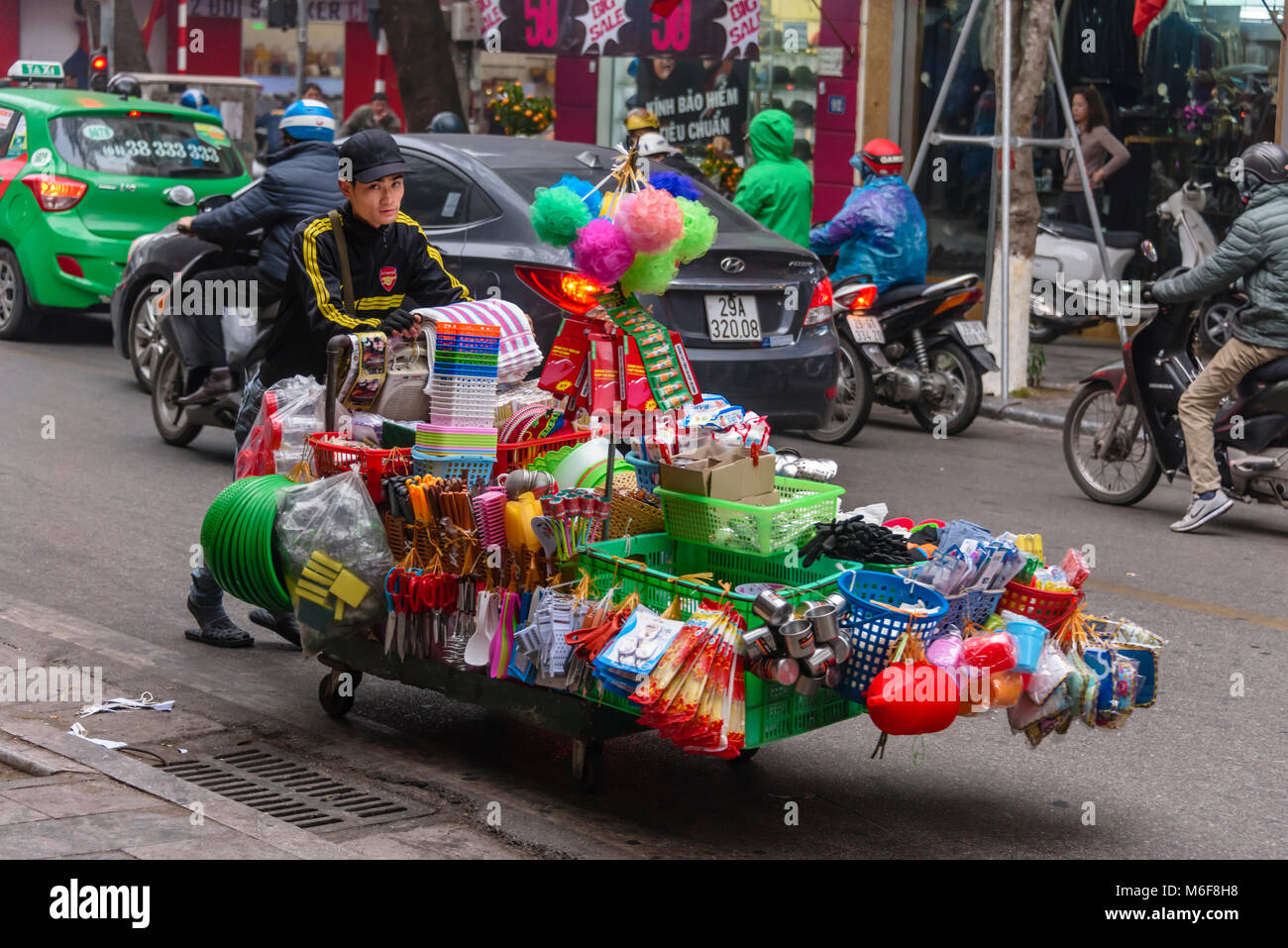 Un homme pousse une charrette chargée avec les marchandises à vendre à Hanoi, Vietnam Banque D'Images