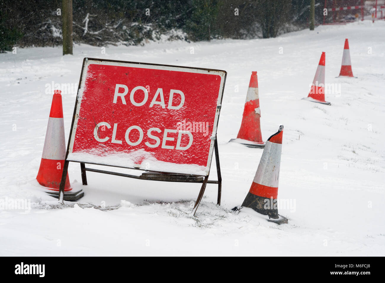 Un Red Road Closed sign et cônes couverts en neige fraîche sur une voie dans le Hampshire, en Angleterre. Prise le 2 mars 2018. Banque D'Images