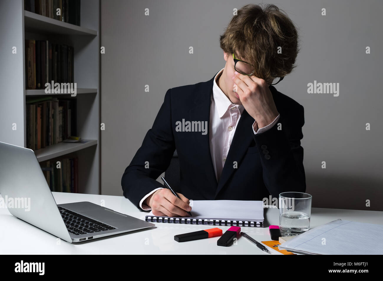 Épuisé employé ou étudiant en fin de travail, heures au bureau moderne pour répondre délai de cession ou d'une tâche d'accueil. Banque D'Images