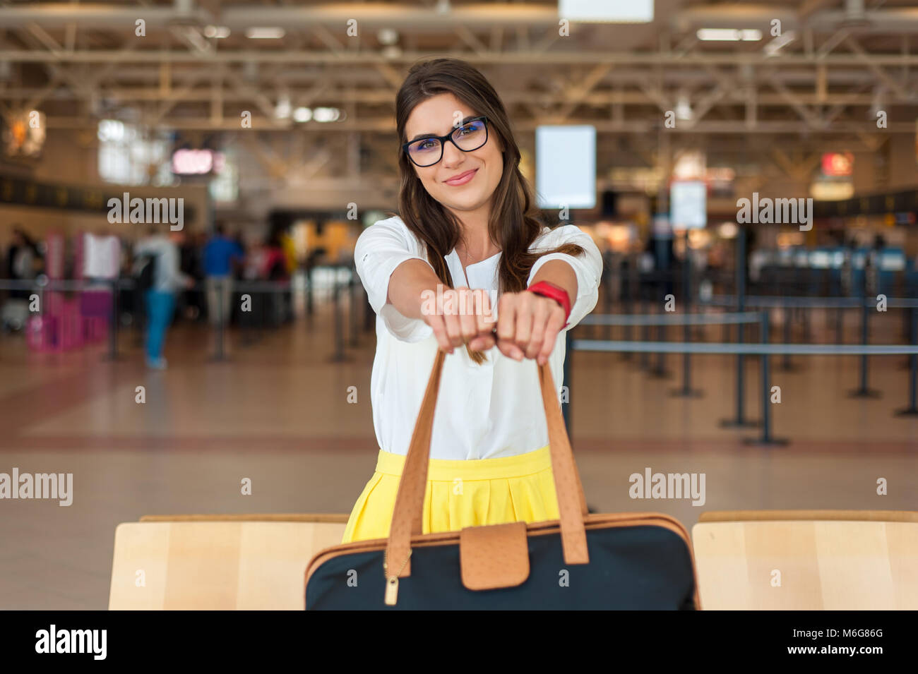 Jeune femme avec un sac à main dans les modèles (tenant son assurance, dans  le hall de l'aéroport en attendant son vol Photo Stock - Alamy