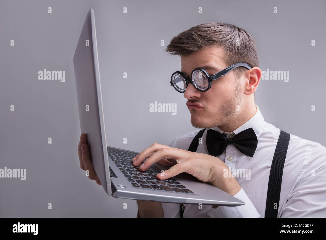 Jeune homme à l'aide de l'ordinateur portable sur fond gris Banque D'Images