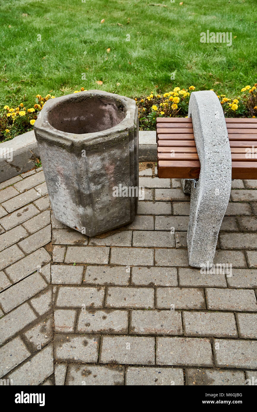 Banc de rue en béton et poutres en bois se dresse à côté d'une poubelle en béton dans le parc public Banque D'Images