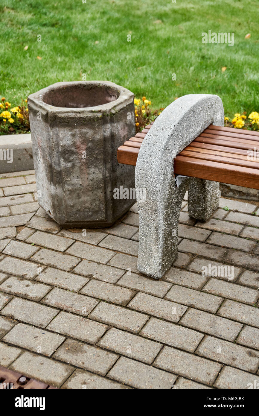 Banc de rue en béton et poutres en bois se dresse à côté d'une poubelle en béton dans le parc public Banque D'Images