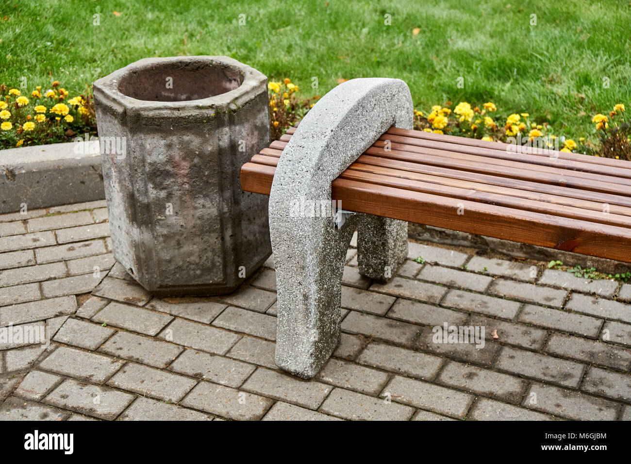 Banc de rue en béton et poutres en bois se dresse à côté d'une poubelle en béton dans le parc public Banque D'Images