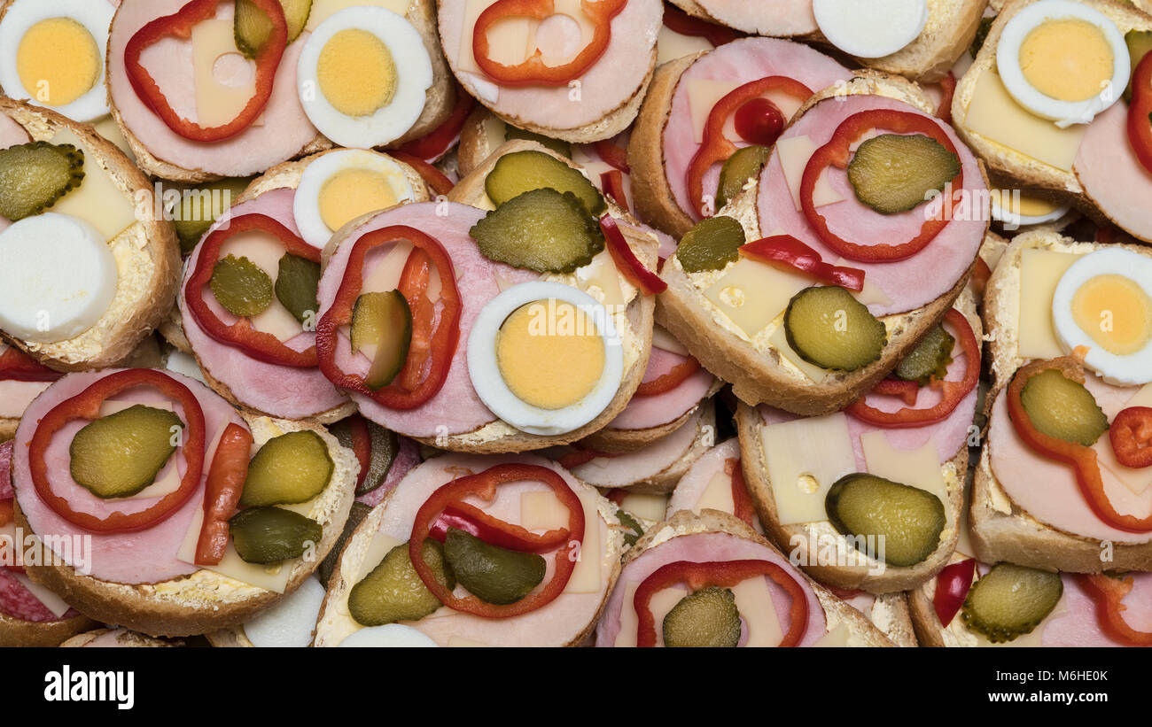 Ouvrez-face des sandwiches gastronomiques comme arrière-plan. La texture colorée à partir de tranches de pain avec jambon, fromage, oeufs durs, poivron et concombre. Banque D'Images