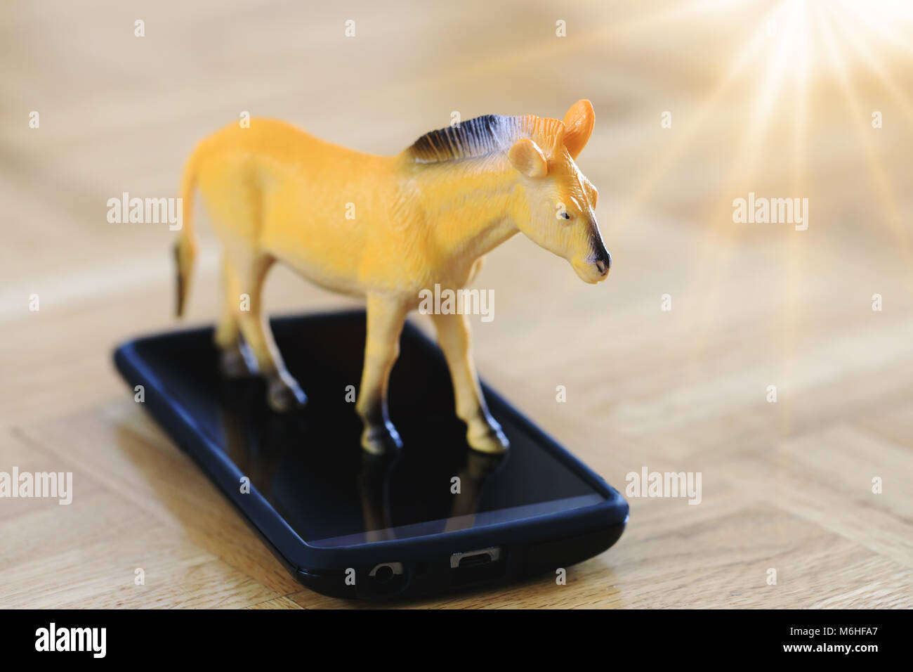 Du vrai cheval jouet en action de courir sur la surface de l'écran de l'appareil. Grande photo pour l'industrie, la technologie mobile gadgets contexte & concept. Banque D'Images