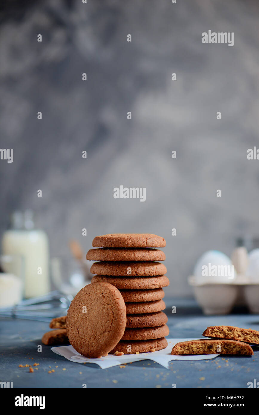 Pile de sarrasin sucre cookies sur un arrière-plan en pierre avec des ingrédients hors focus. Concept de cuisson en high key avec copie espace. Banque D'Images