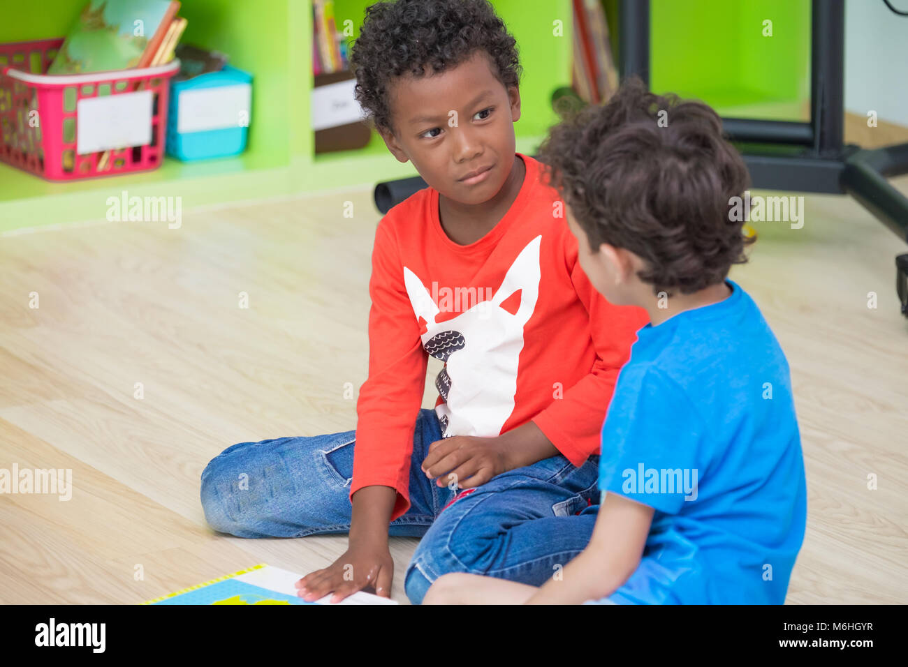 Deux garçon enfant assis sur le sol et de prendre dans la bibliothèque de l'école maternelle préscolaire,éducation concept.Les enfants de la diversité Banque D'Images