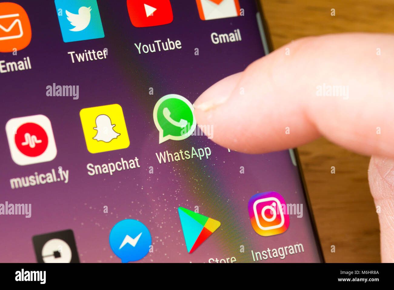 Gros plan de l'application WhatsApp sur un smartphone sélectionné par le doigt d'une femme pointant vers l'application sur le écran du téléphone cellulaire Banque D'Images