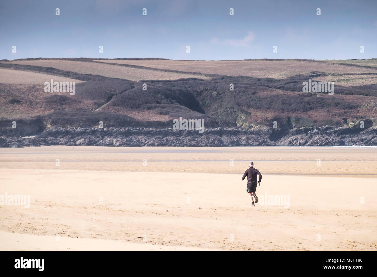 Un homme qui court le long de plage de Crantock en Newquay Cornwall. Banque D'Images
