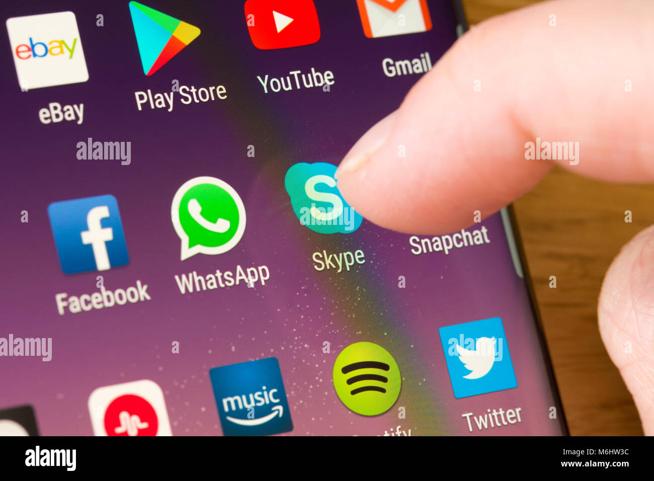 Gros plan de l'application Skype sur un smartphone sélectionné par le doigt d'une femme pointant vers l'application sur le écran du téléphone cellulaire Banque D'Images