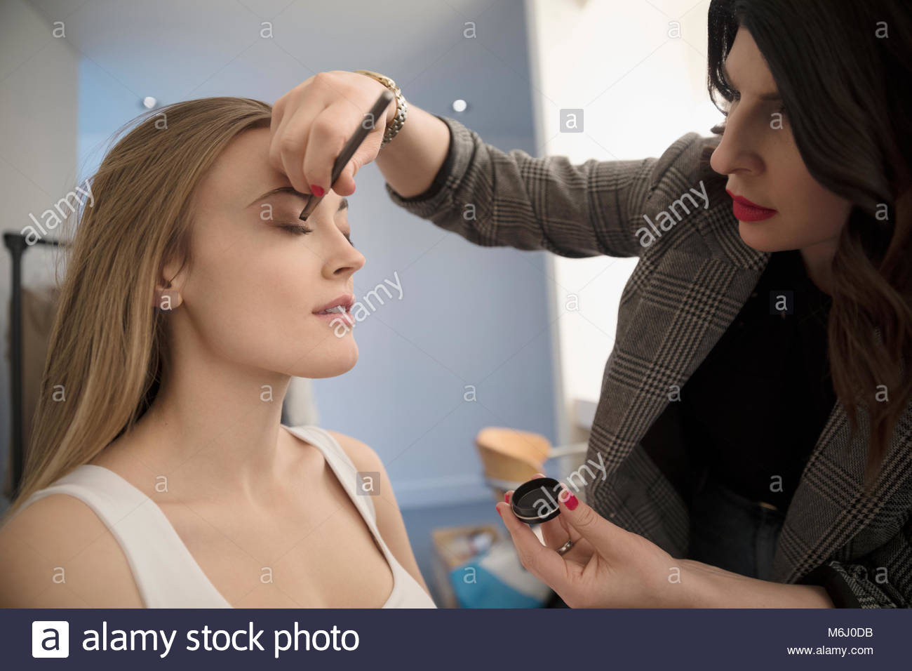 Artiste de maquillage femme appliquant le maquillage au modèle, la préparation à la pousse de photo Banque D'Images