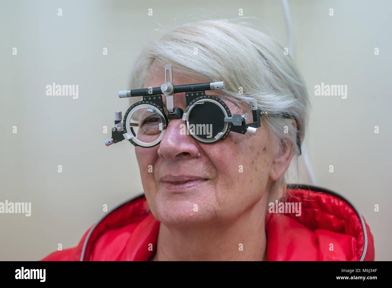 Zrenjanin, Serbie, février 2018 : woman wearing phoropter ou châssis d'essai et à l'œil au graphique de test au cours de test de la vue à optometri Banque D'Images