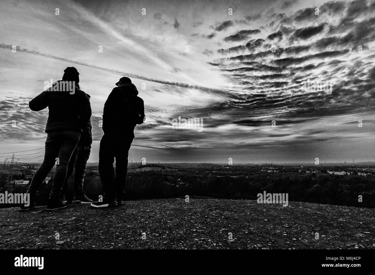Deux hommes, une femme, des amis sur une colline au coucher du soleil Banque D'Images