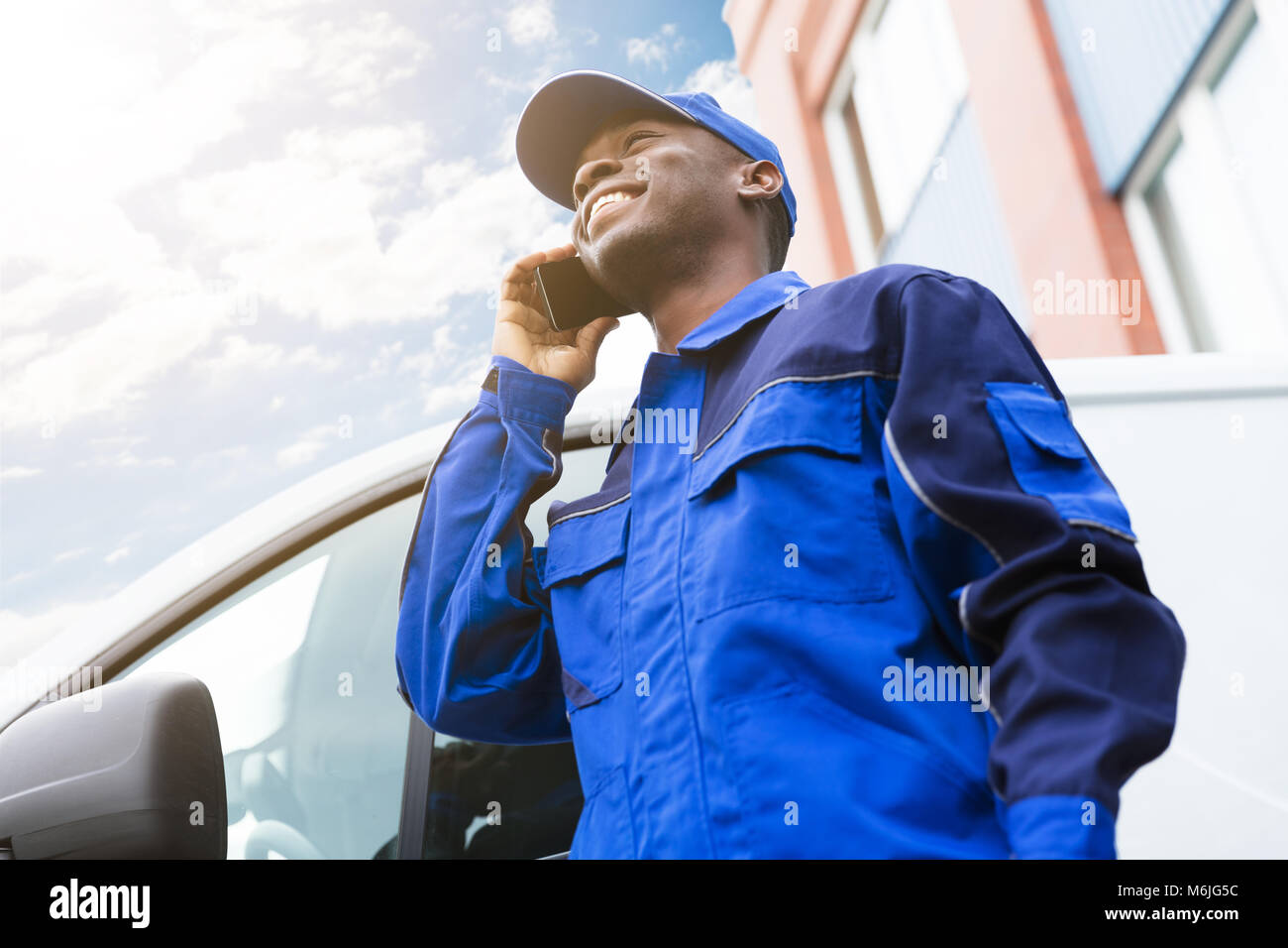 Low Angle View of Young Man Standing livraison près de Van Talking On Cellphone Banque D'Images