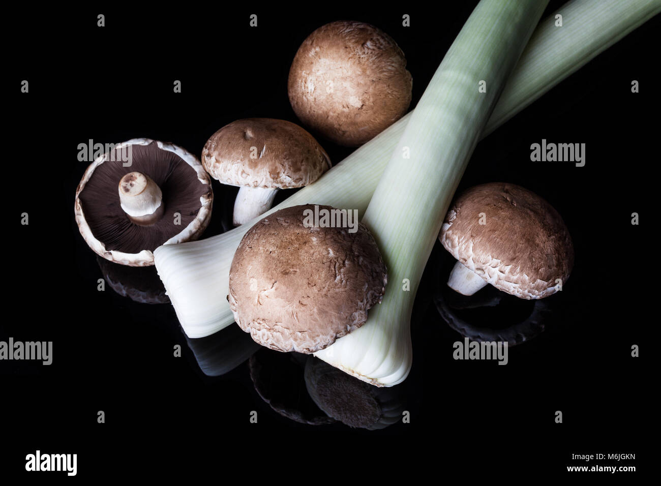 Les poireaux et champignons brune sur fond noir d'en haut Banque D'Images