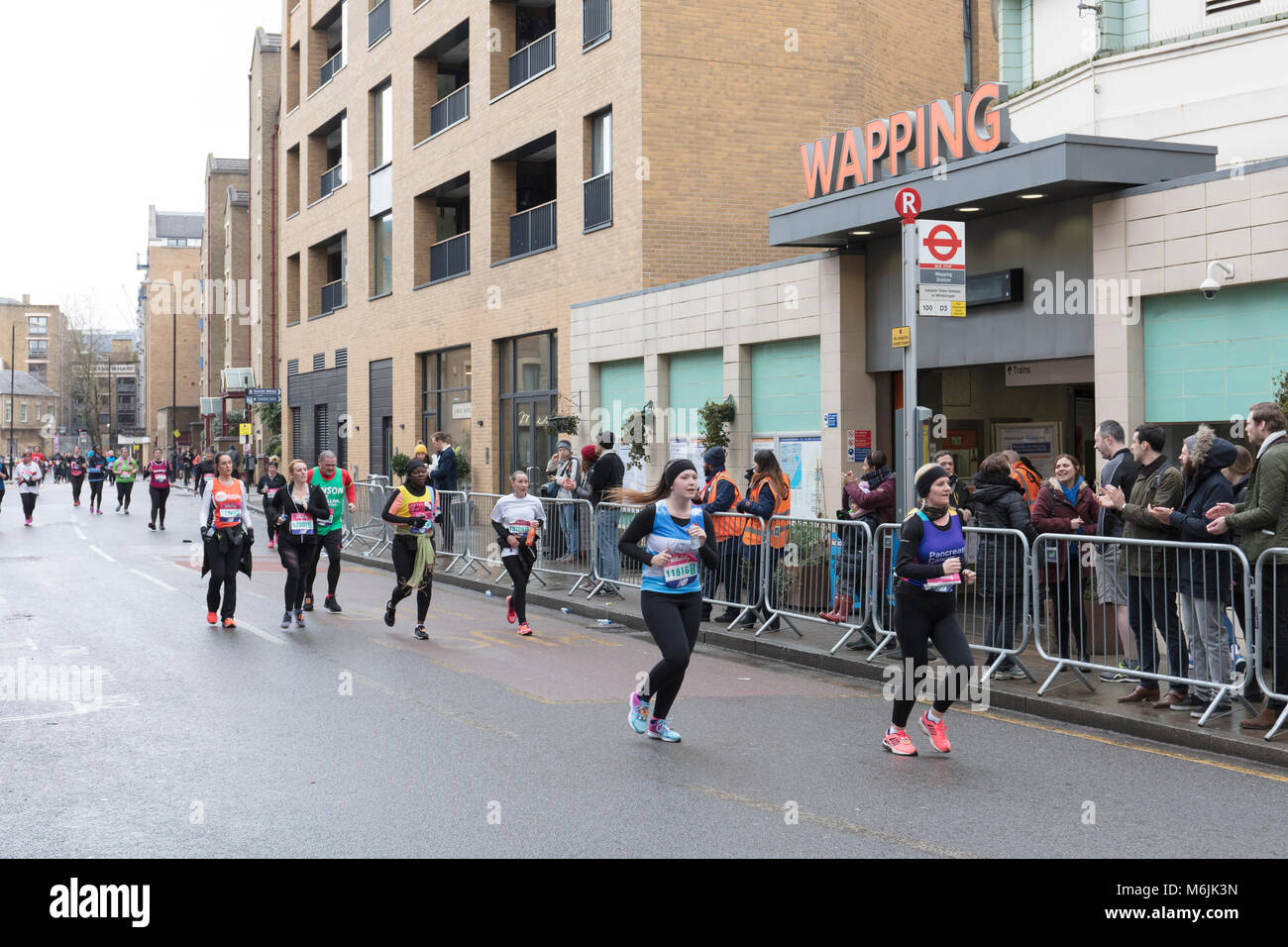 Les coureurs de la grande vitalité du demi-marathon sur les rues pavées de Wapping, East London Banque D'Images