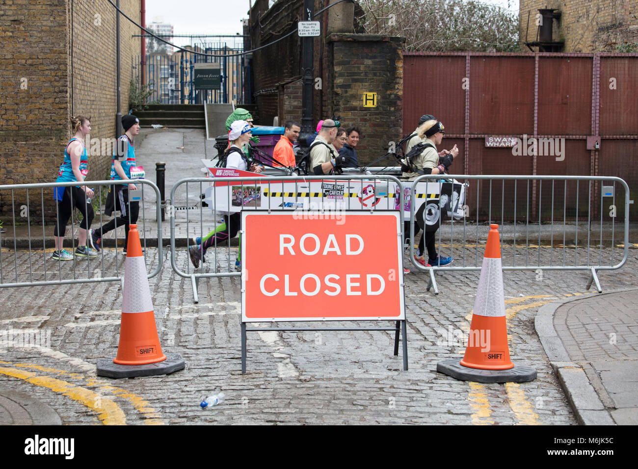 Les coureurs de la grande vitalité du demi-marathon route du col de signe clos sur les rues pavées de Wapping, East London Banque D'Images