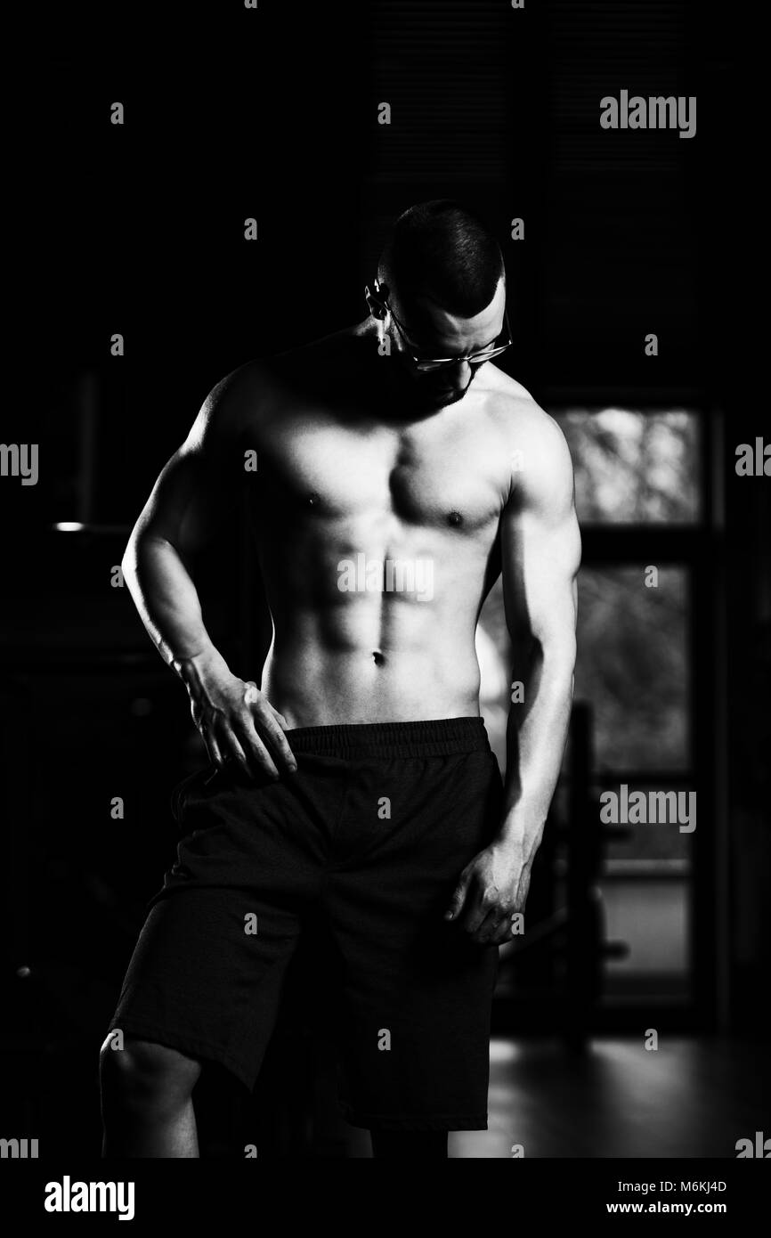 Portrait d'un jeune Nerd Forme Physique Homme montrant son corps bien formé - Athletic musculaire Fitness Model Posing Bodybuilder Exercices après Banque D'Images