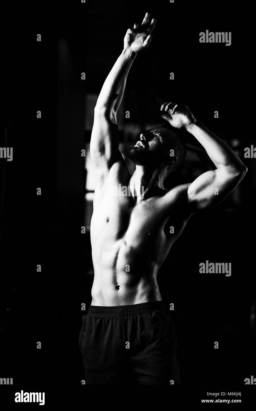 Beau Geek Homme debout forte dans la salle de sport et Flexing Muscles musculaire - Fitness Model Posing Bodybuilder athlétiques exercices après Banque D'Images
