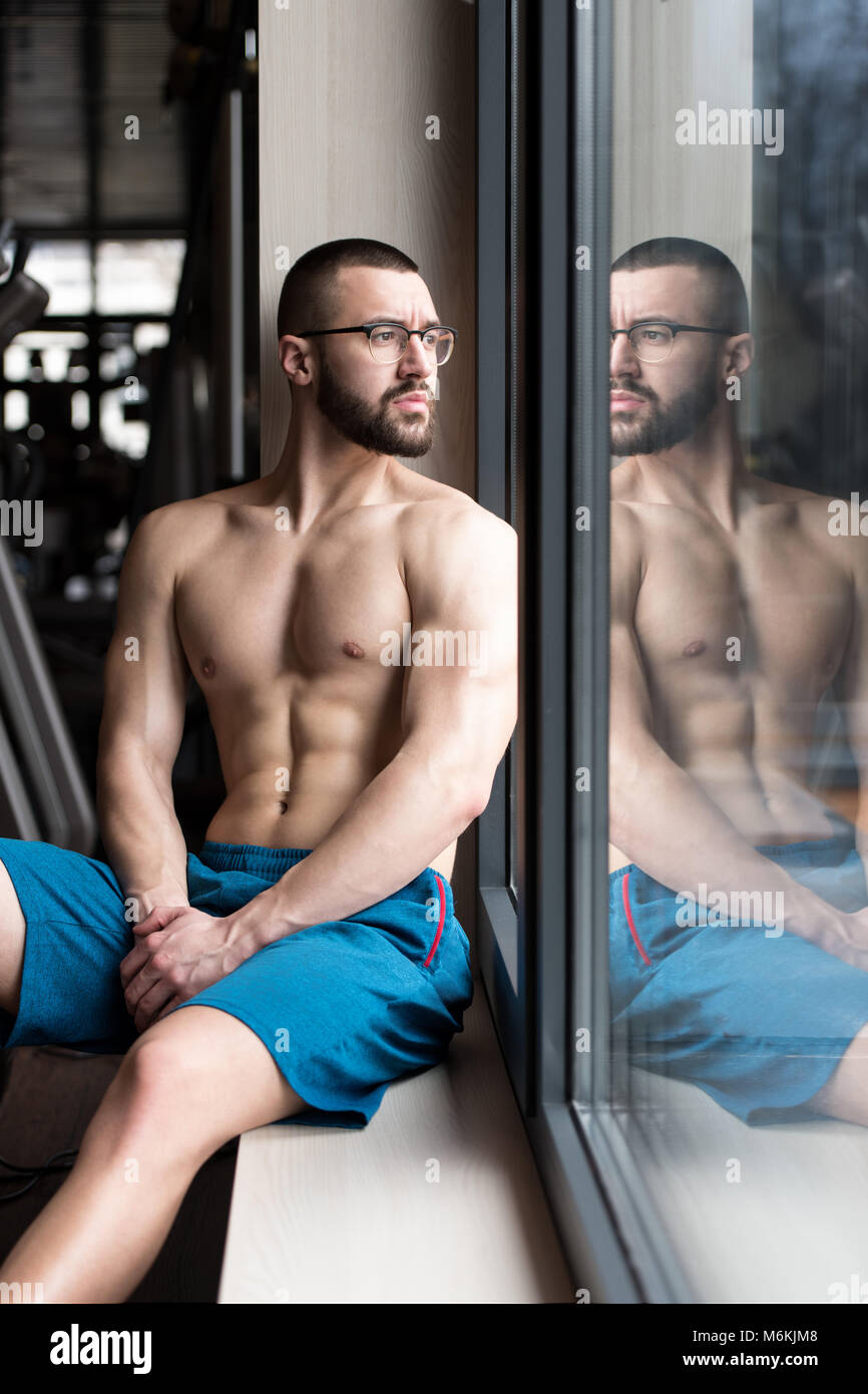 Beau Beau et séduisant jeune homme avec corps musclé se détendre dans la salle de sport Banque D'Images