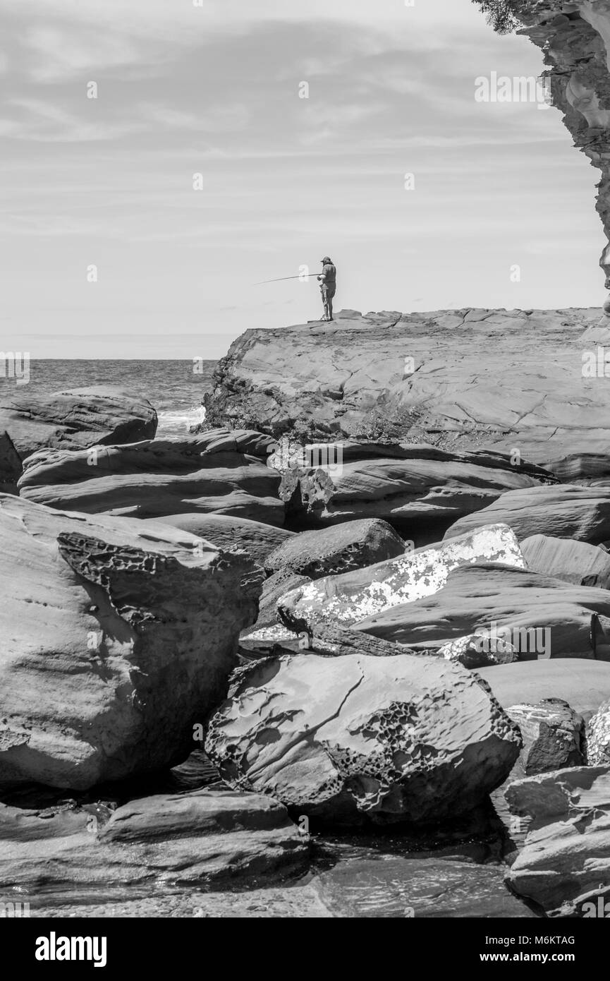 Pêche pêcheur à des formations de roche de grès à Avoca Beach. L'AUSTRALIE Banque D'Images