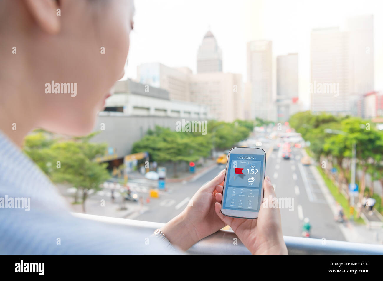 Charmante femme looking at smartphone d'indice de la qualité de l'application pour savoir comment la pollution est à l'extérieur du bureau sur les heures de pointe. Banque D'Images