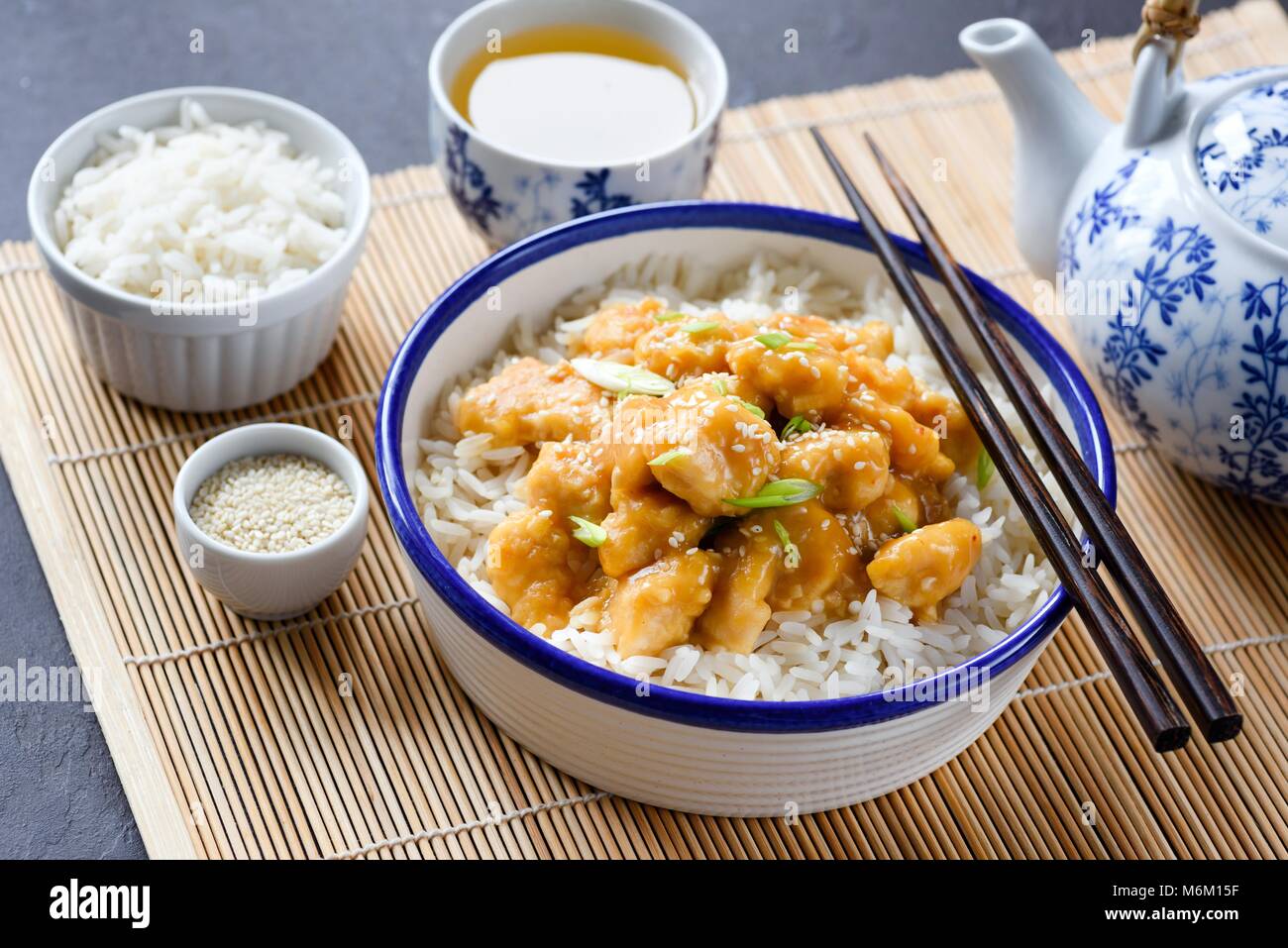 La cuisine chinoise bol de riz avec le poulet et les graines de sésame, Chine théière et thé vert. Fond bambou makisu Banque D'Images