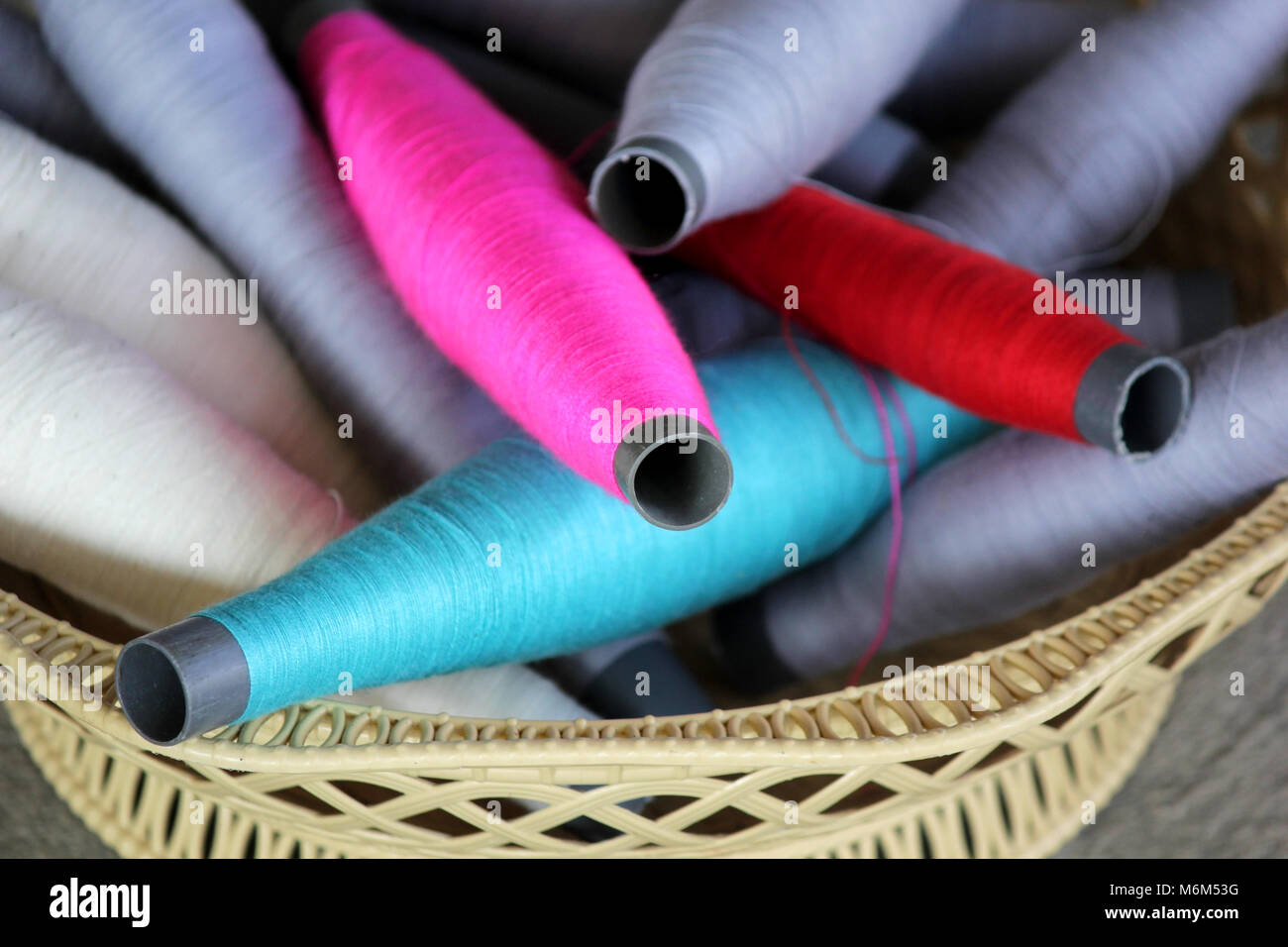 Bobines en bois coloré thread dans le panier, le tissage traditionnel de la soie thaïlandaise Banque D'Images