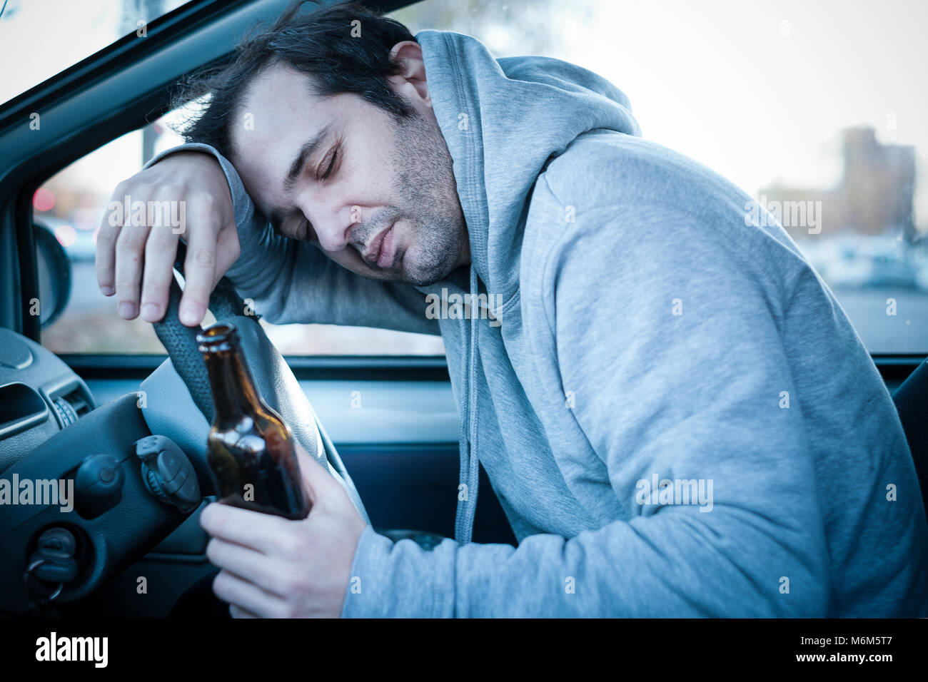 Jeune homme au volant de sa voiture alors que la consommation d'alcool et s' endormir , effet bleu ajouté pour augmenter le théâtre Photo Stock - Alamy