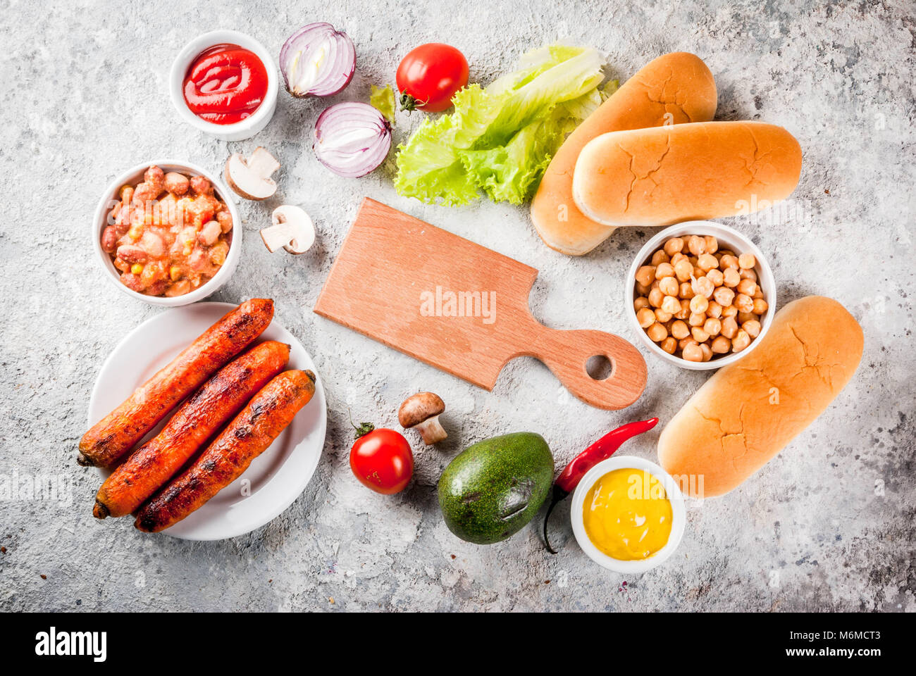 Pour les différents ingrédients des Vegan Carotte Hot-dogs, avec l'oignon frit, avocat, piment, champignons, tomates et haricots, pierre grise copie d'arrière-plan Banque D'Images