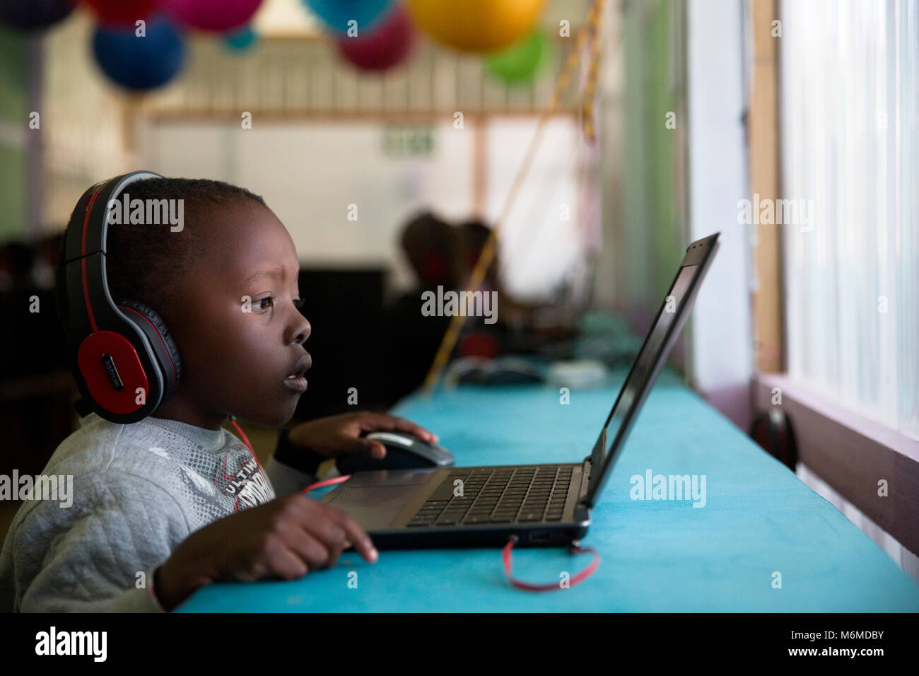 Garçon enfant assis et de concentrer à un ordinateur portable Banque D'Images