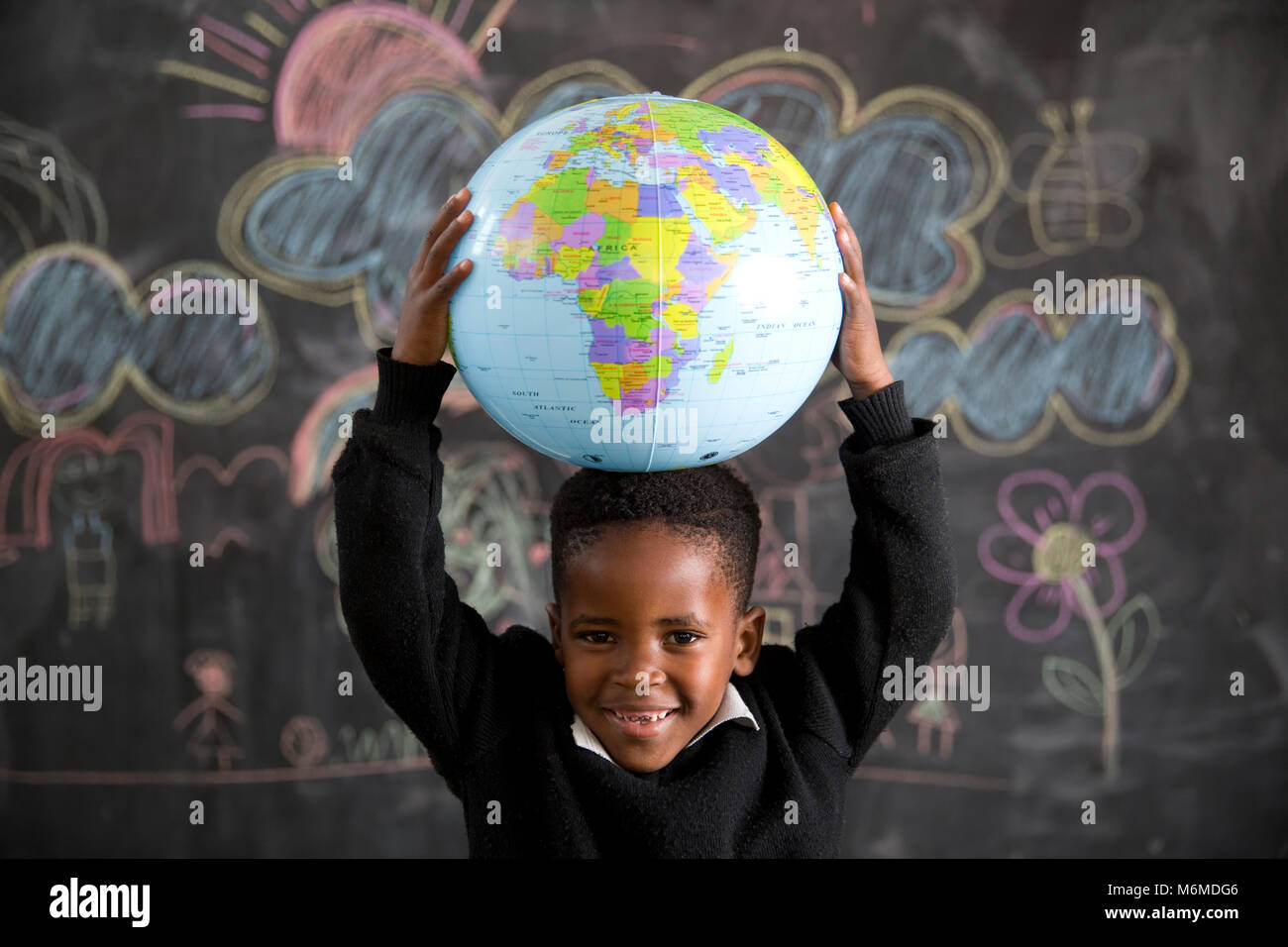 School boy holding a globe sur sa tête Banque D'Images