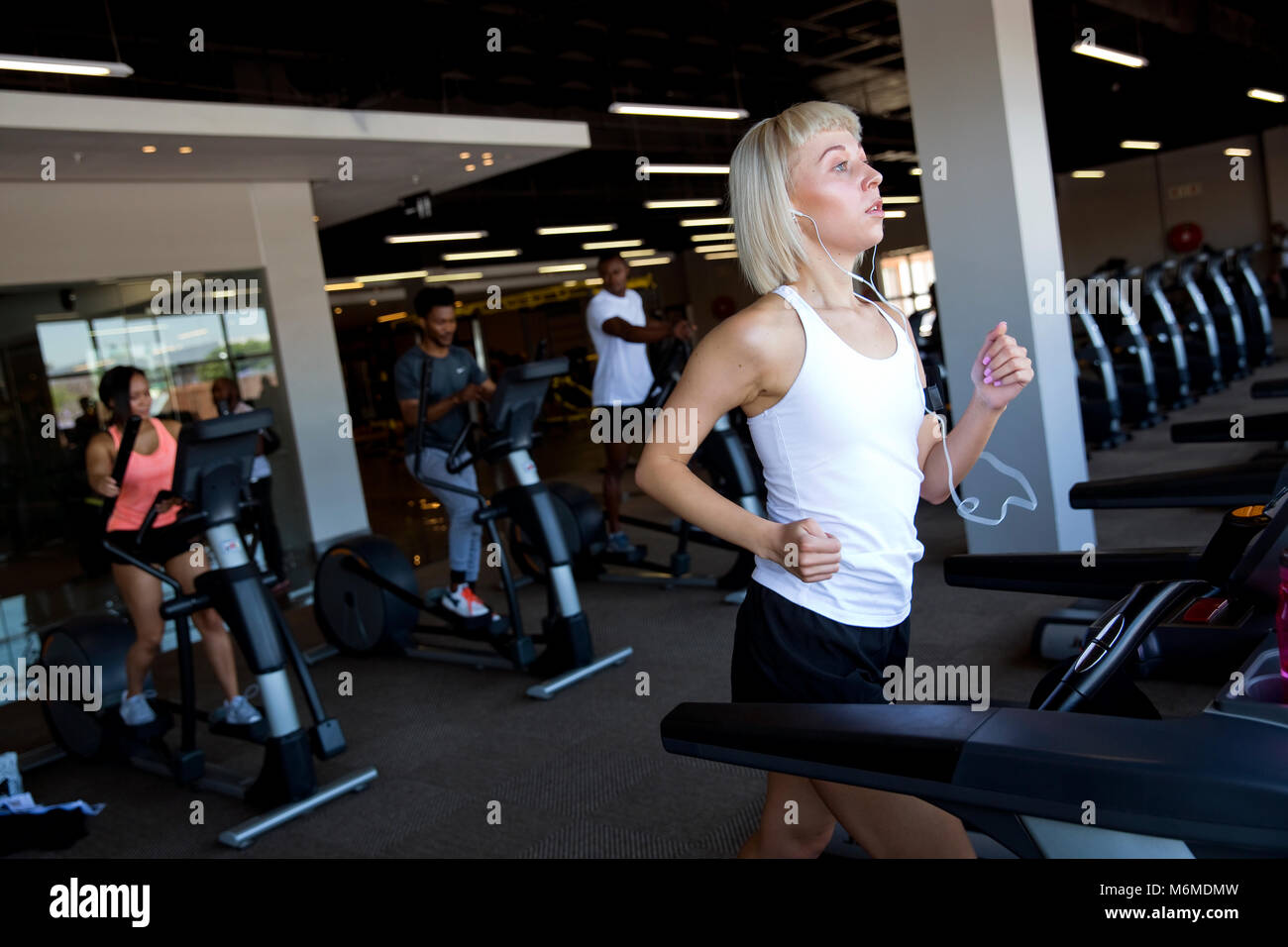 Caucasian woman running sur tapis roulant à la salle de sport Banque D'Images