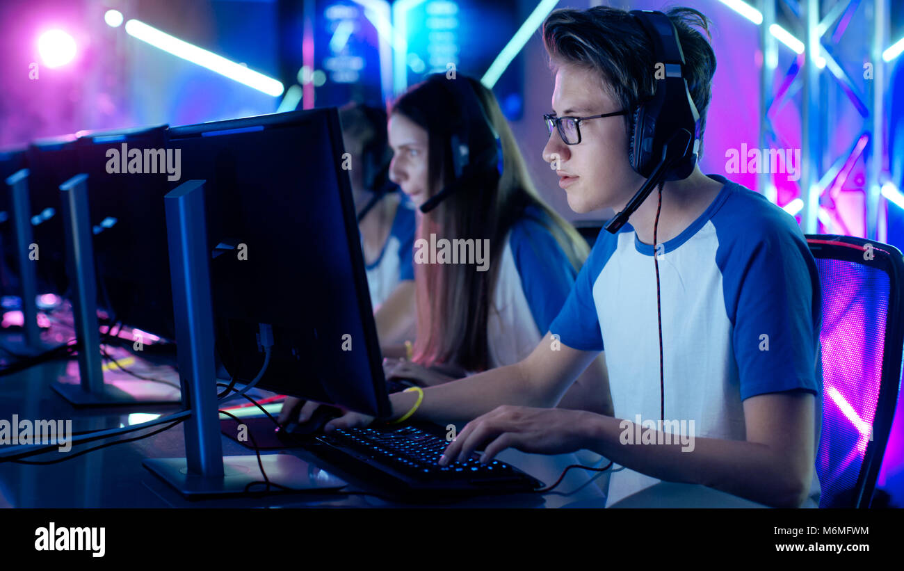 Équipe de Professionnels du Cybersport joueurs de jeu jeux vidéo sur un Cyber Games tournoi. Les filles et les garçons ont les écouteurs, Arena est allumé avec néon Banque D'Images