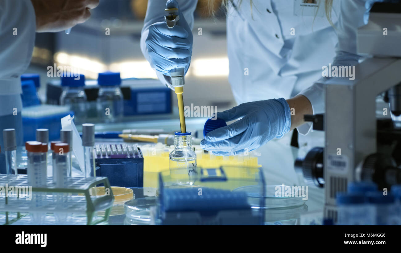 Femme Chercheur scientifique utilise des tubes à essai de remplissage Micropipette. Chercheur scientifique travaille dans une équipe de scientifiques d'essayer de traiter des maladies mortelles Banque D'Images