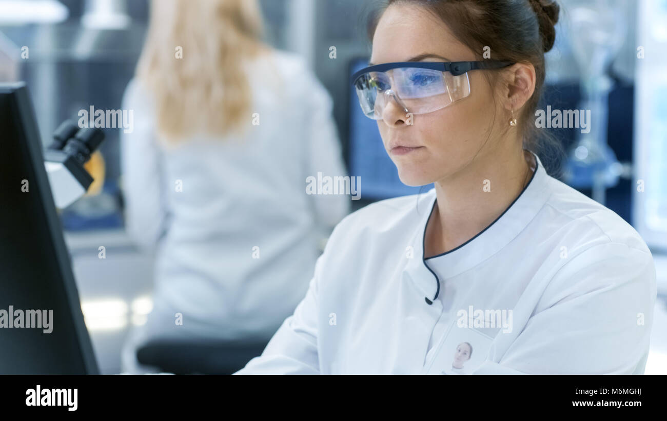 Chercheur scientifique médical en utilisant l'ordinateur personnel. Elle travaille dans un laboratoire lumineux moderne. Banque D'Images