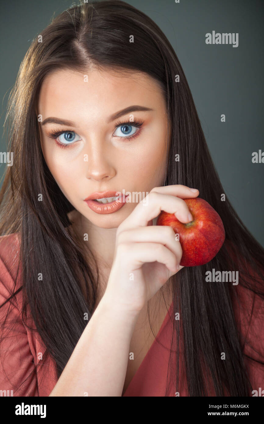 Un joli teenage girl holding a red apple et regardant la caméra. Banque D'Images